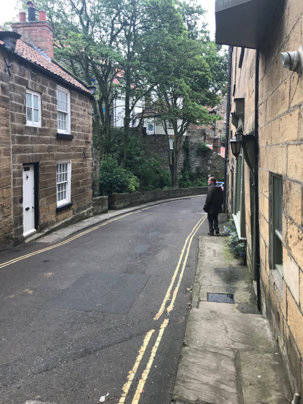 B. standing in a narrow sloping street.
