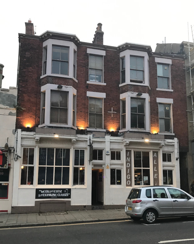A Victorian-ish three storey house frontage with the name Indigo Alley painted on the walls.