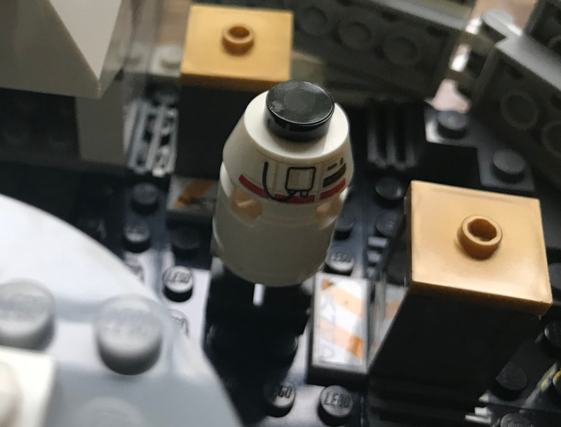A round LEGO droid next to some LEGO boxes.