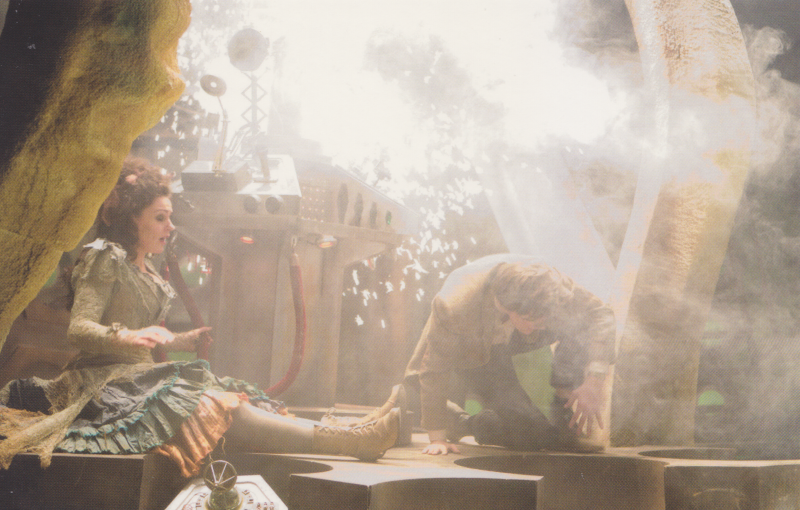 Screenshot from The Doctor's Wife.  Interior of the the Tardis.  Idris sits to the right of the image.  There is a lot of smoke and confusion and sparks.  The Doctor is crawling to the left.