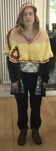 Me wearing a brown and yellow/white crocheted hood, full length portrait.