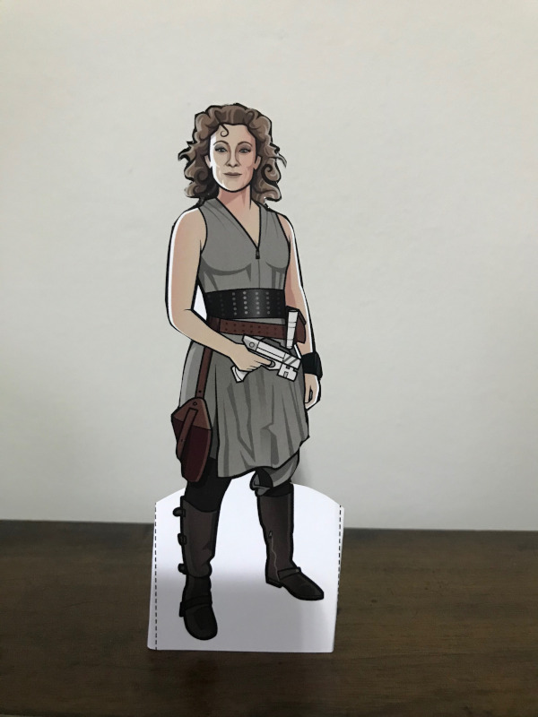 River Song Paper doll in the sort of green bunched skirt outfit with a wide belt and gun.