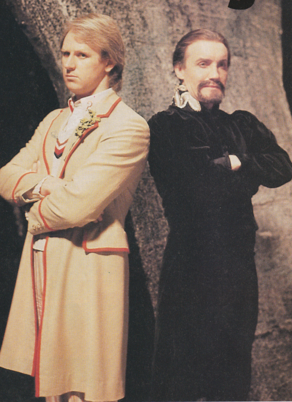 Publicity still of the Fifth Doctor and the Ainley Master standing back to back, arms crossed.