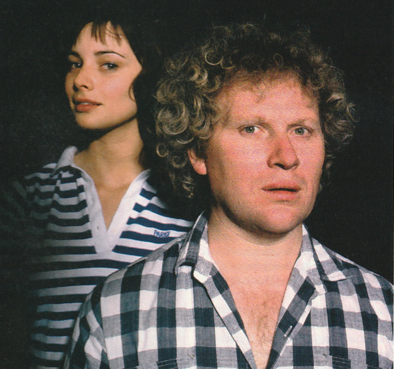 Publicity still of Colin Baker and Nicola Bryant for the Slipback Audio.  Nicola in a blue and white striped polo shirt while Colin is in a blue and white checked shirt.