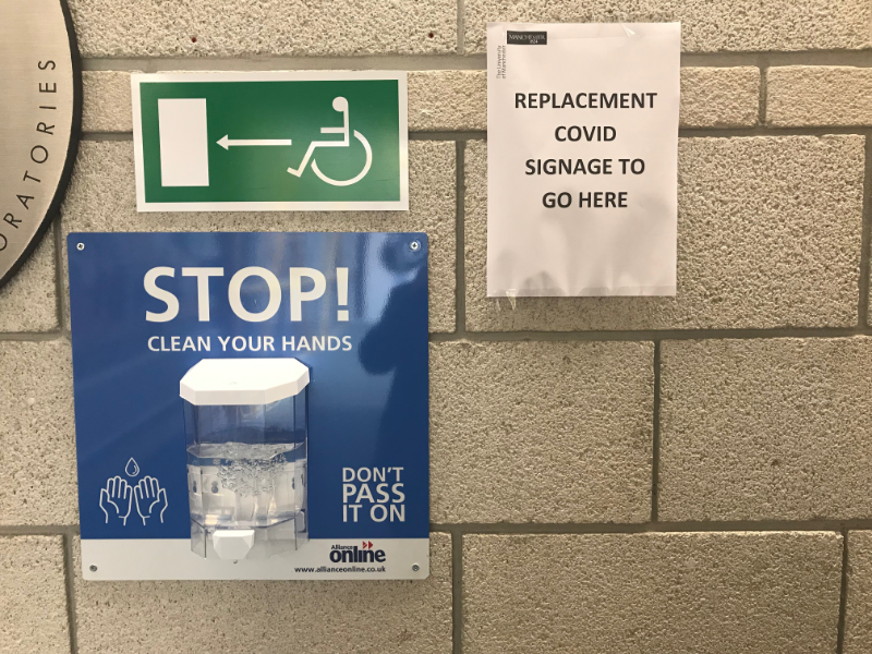 A4 paper sign saying Replacement Covid Signage to go here.  It is next to a sign for the disabled toilet and a hand sanitising station.