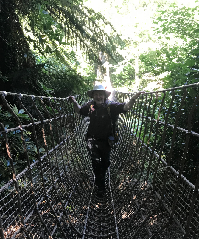 Himself crossing a rope bridge, grinning.
