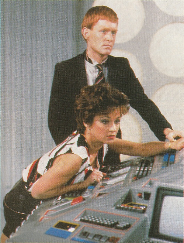 Tegan and Turlough at the Tardis Console.  Tegan leaning across it.