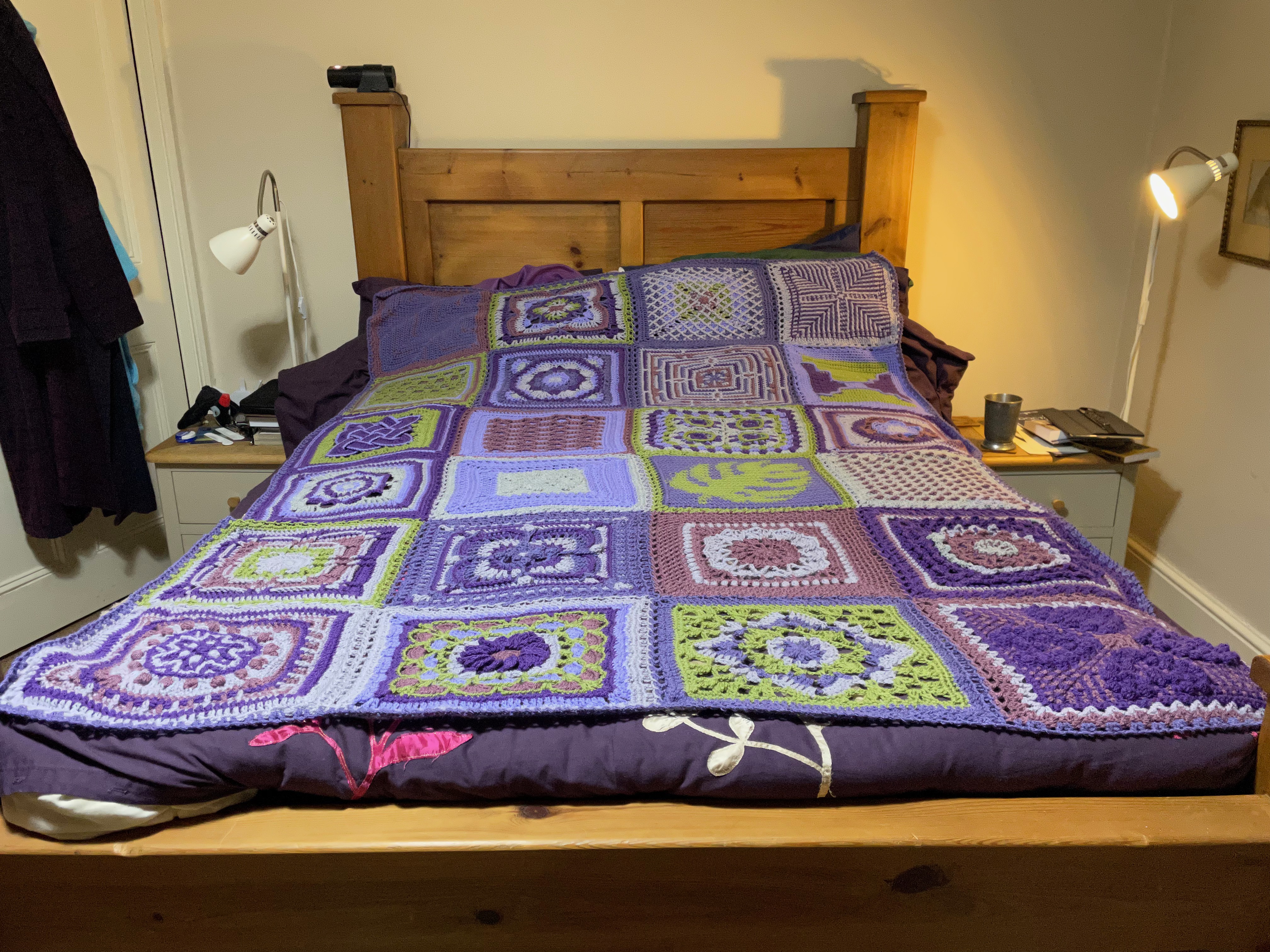 Blanket made up of crochet squares in a range of purples