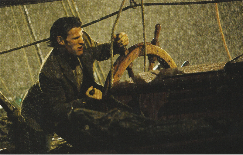 The Eleventh Doctor at the wheel of a sailing ship in a storm.