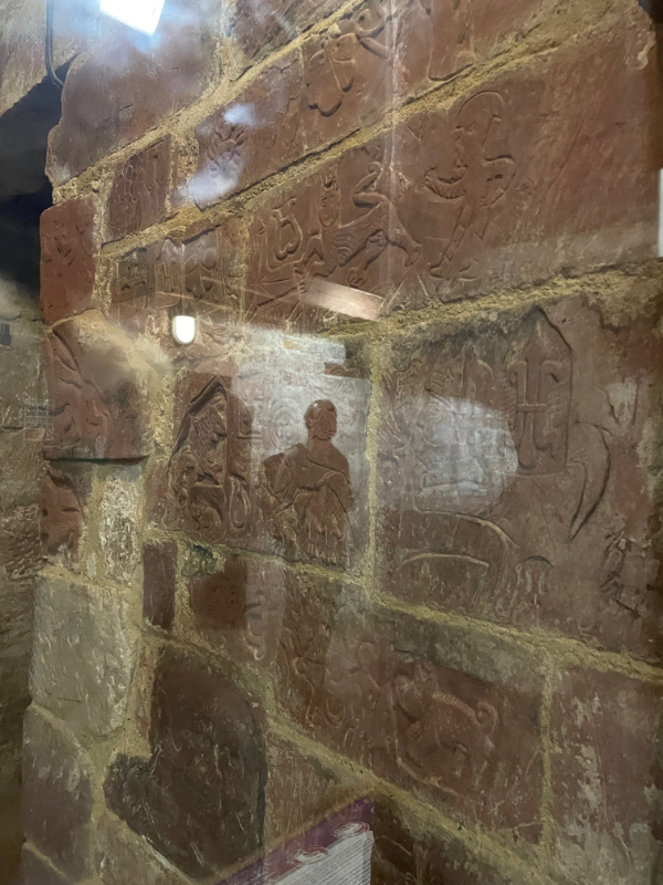 A glass pane through which can be seen carved bricks.