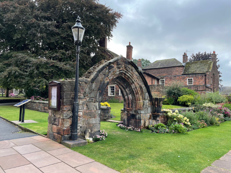 Small arch in a garden border with an old-style lamp post.