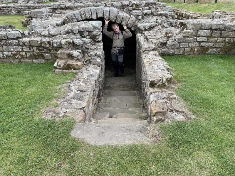 B peering out from under a stone are.  Stone steps lead down to it between walls.