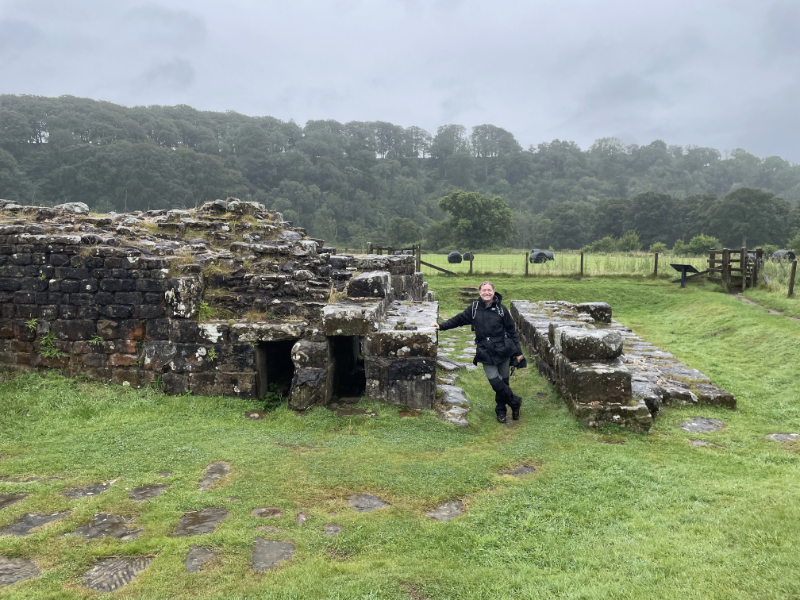 B standing between two low stone structures. One is a self-contained rectangle while the other becomes part of a wall.