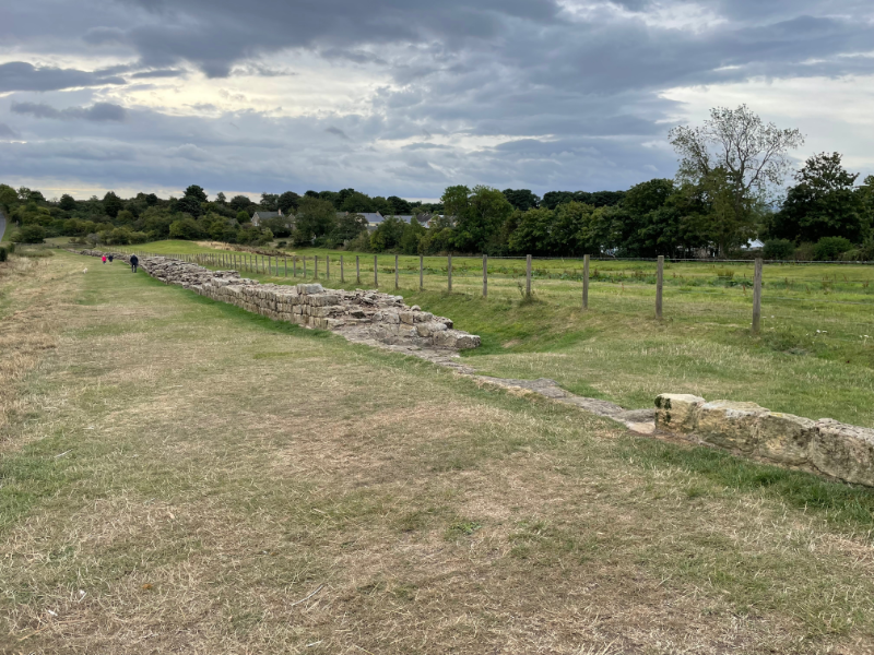Longish stretch of low wall next to a fence.