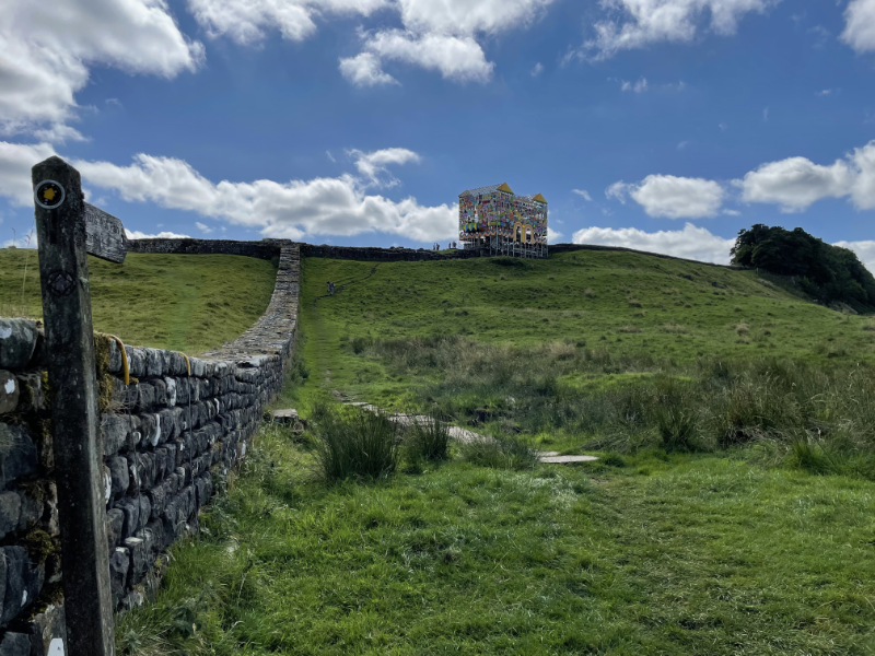 A sign post points back along Hadrian's Wall to the fort.  The mock gatehouse is very visible.
