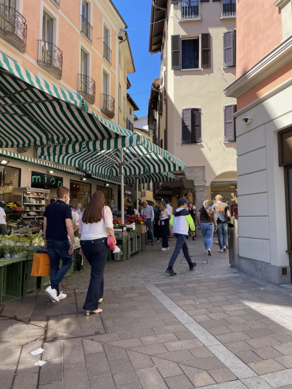 Busy narrow street with plastered houses and stalls selling fruit.