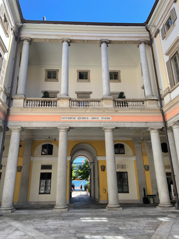 Courtyard of a building with pillars supporting balcony and roof.
