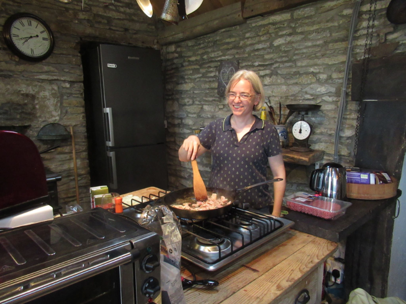 Me grinning, cooking in a large black pan with a wooden spoon