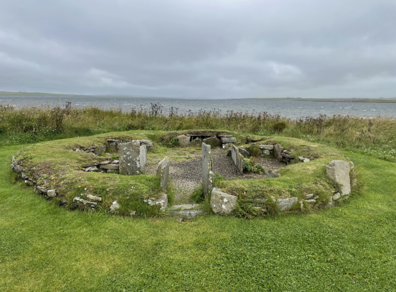 Low walls of small round building with chambers/beds visible within.