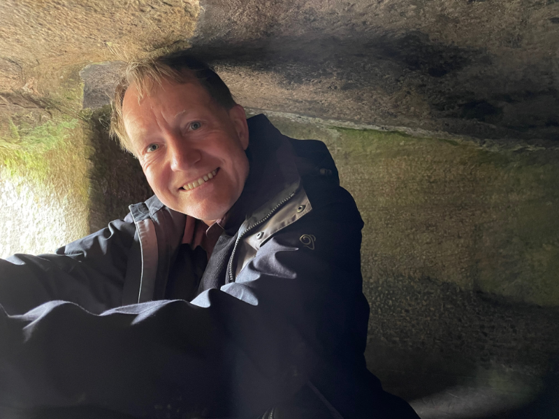 B. seated inside the stone.  His head just touches the roof