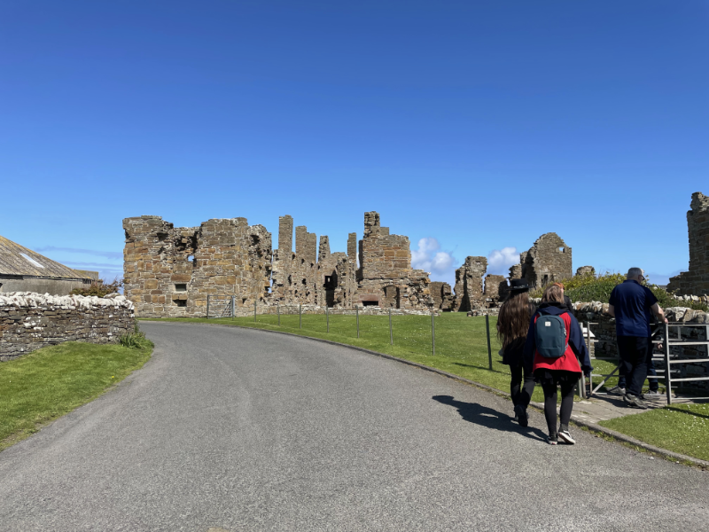 Ruined palace from the road. People entering the gate.