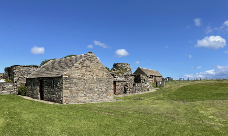 Stone buildings in a grassy field.
