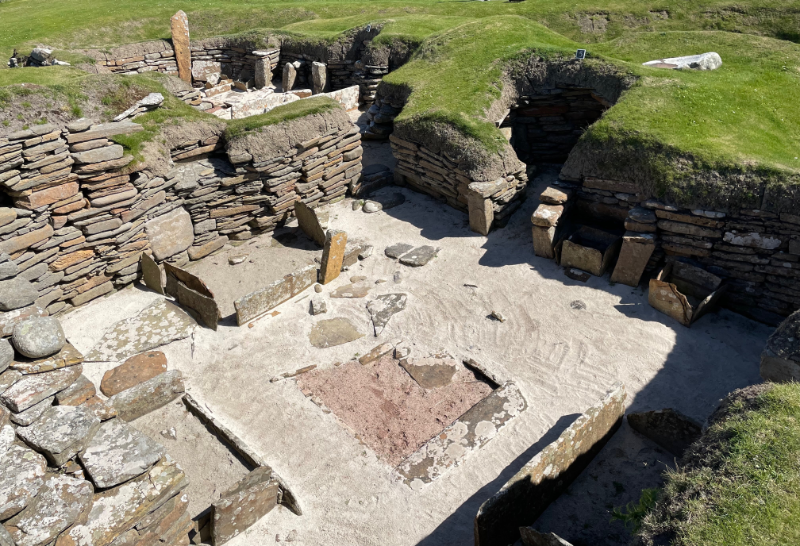 Looking down into a stone-walled room. Two box structures against the wall.