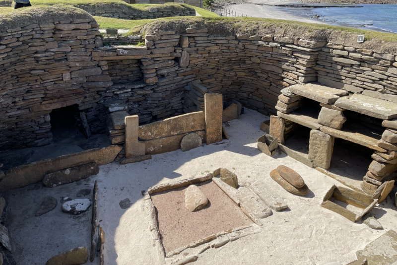 Looking down into a stone-walled room, showing a box bed and a dresser.