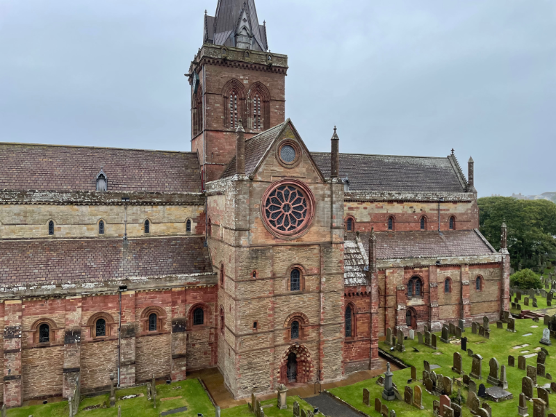 Outside of the Cathedral showing graveyard, tall central tower and circular window.