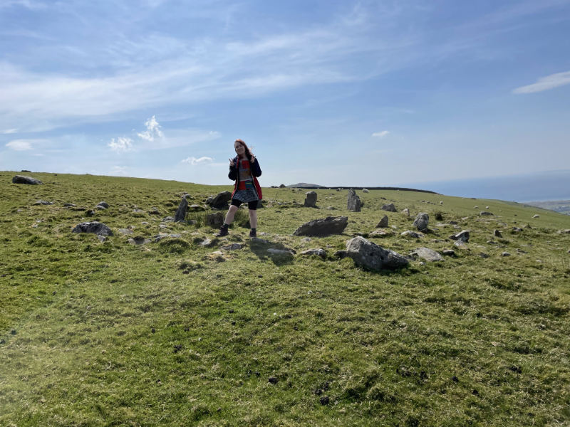 Marmalade Sparrow standing in front of a tiny stone circle.