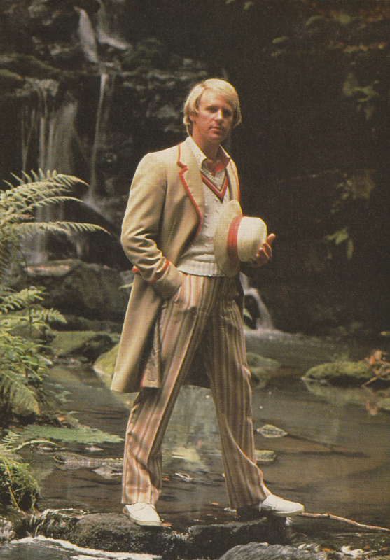 The Fifth Doctor.  Publicity still standing on stepping stones across water with greenery and a waterfall in the background.