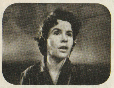 Black and White head shot of a woman with a 1950s hairstyle, wearing headphones with a microphone.