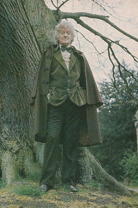Jon Pertwee as the third Doctor in a green velvet jacket and what I believe to be an Inverness cape.  He is standing beneath a tree.  Probably a publicity still for the Time Warrior.