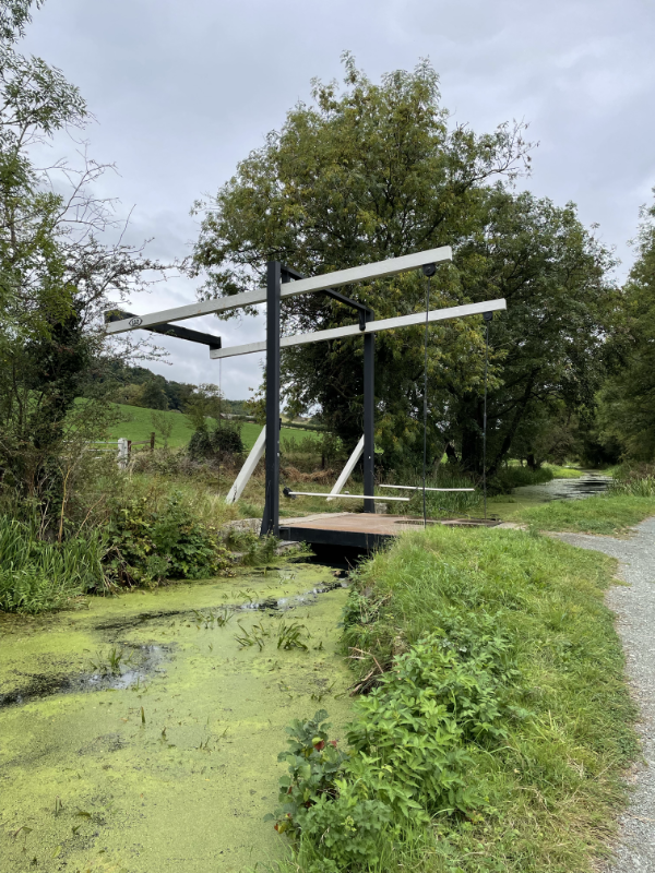 A cantilever bridge. Two upright black posts and then two white crossbars with wires descending to the far side of the bridge.