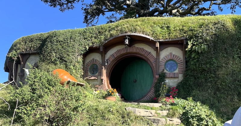 The geen door of Bag End with a pumpkin to one side.