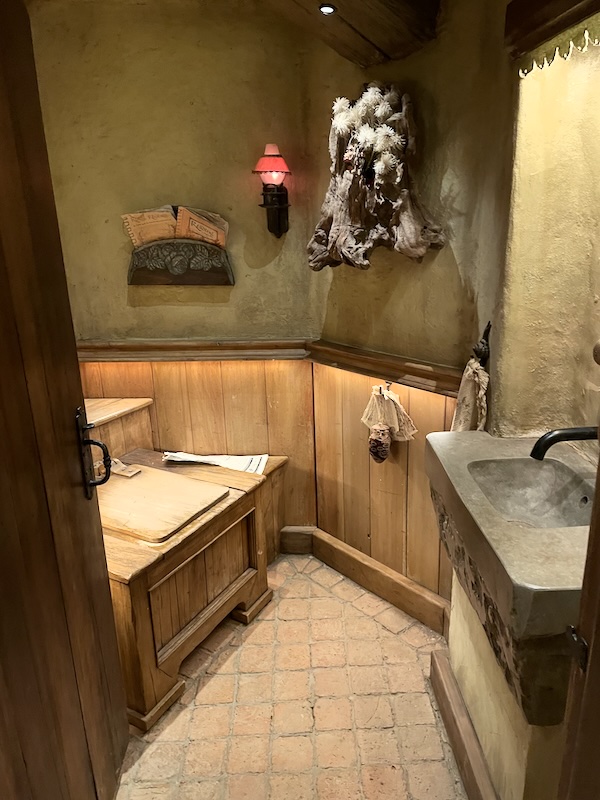 A view into a water closet with a wooden box-like loo and stone basin.