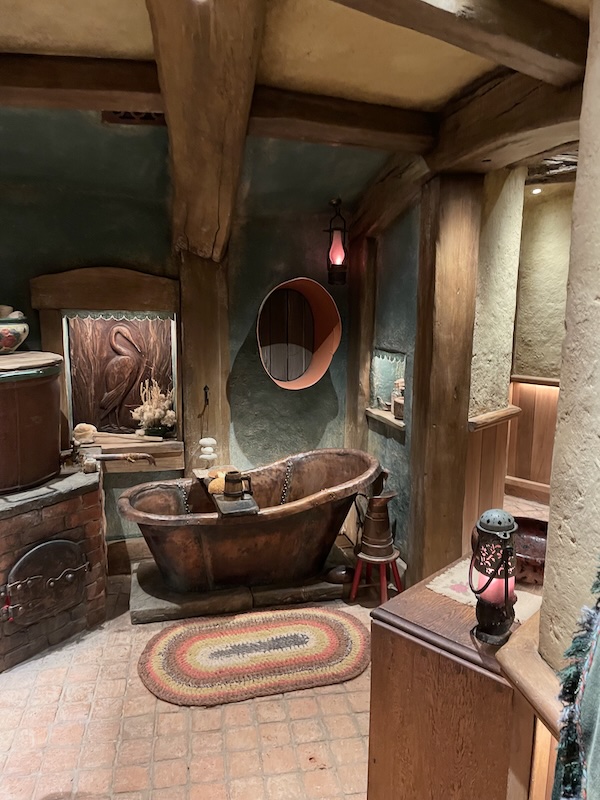A bathroom with green walls and a copper freestanding bath.