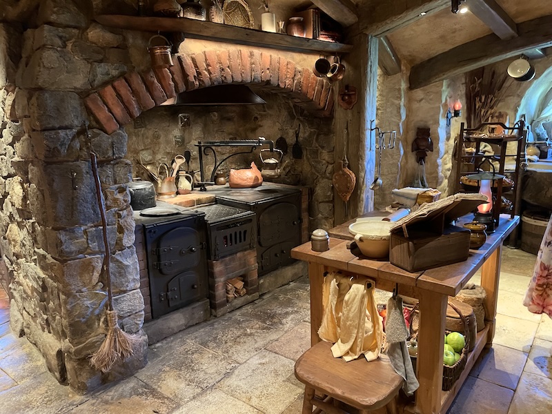A kitchen with a range cooker set into an arch. An island in front is loaded with pots and bowls.