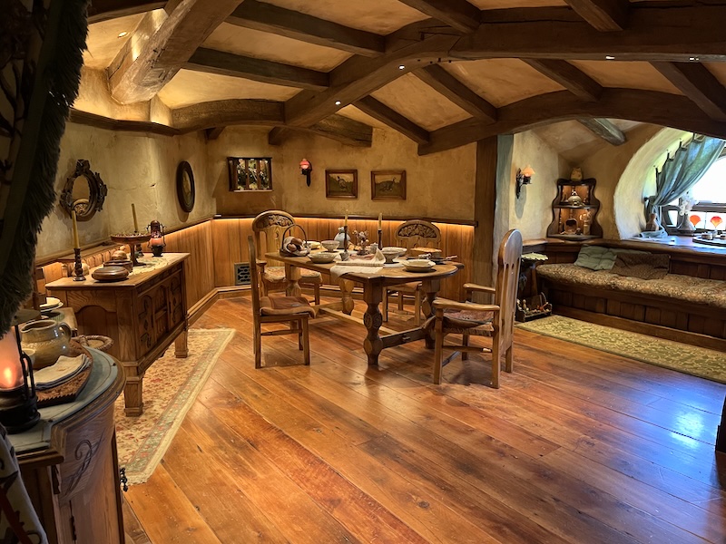 A dining table with four chairs, sideboard and window seat.