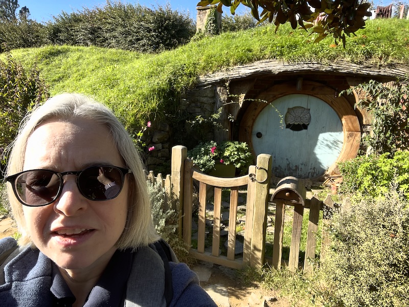 A selfie of me in front of a hobbit hole with a light blue door.