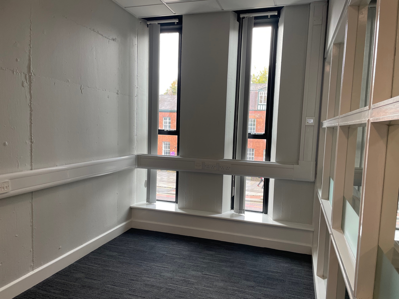 A small empty room with narrow floor to ceiling windows at the far end.