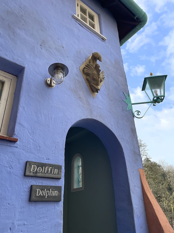 A blue wall with an arch. Signage says Dolffin and Dolphin. A carving above may be a dolphin.