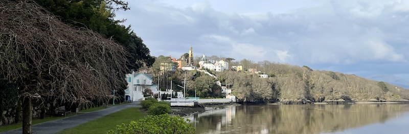A view of Portmeiron from the estuary side walk. The white hotel by the waterside, with the coloured buildings rising above it.