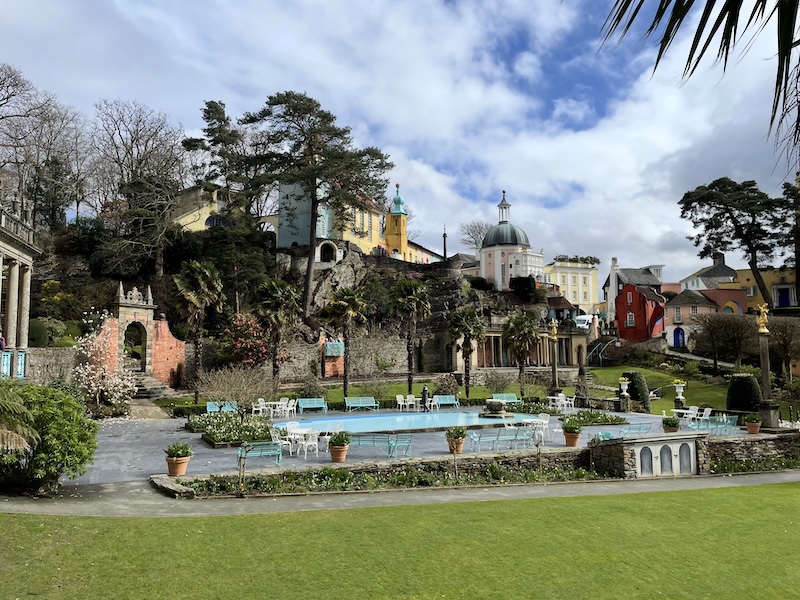 The shallow pool at Portmeirion with the colonnade behind it and coloured buildings rising above.