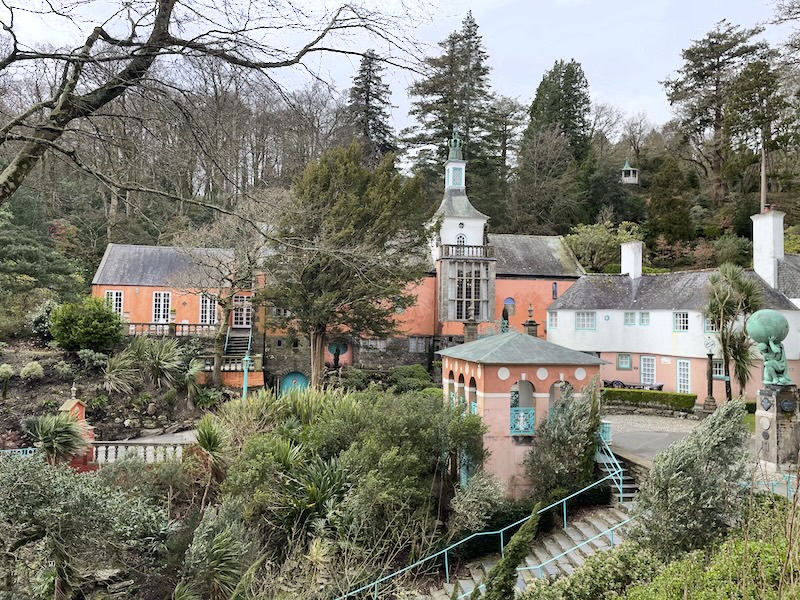 A long red building surrounded by plants and walkways.