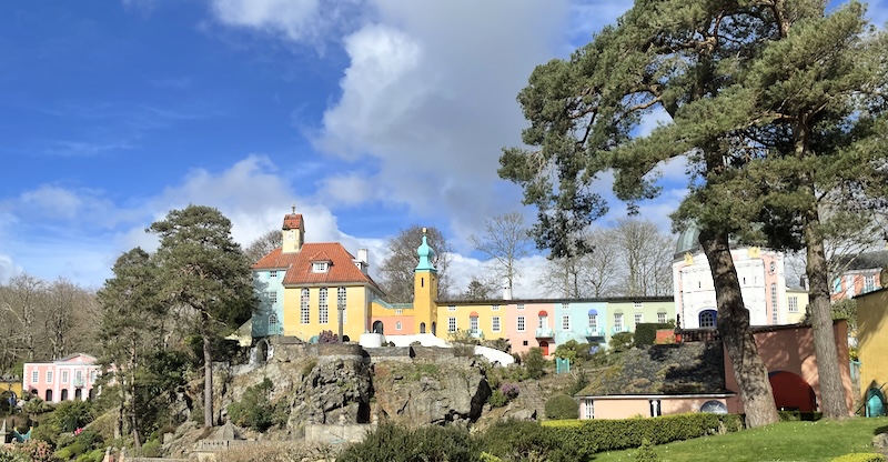 A view of a colonnade of coloured buildings on a cliff.