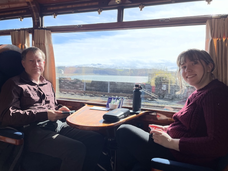 B and Marmalade Sparrow seated by a train window. Blue skies and snow capped mountains beyond!