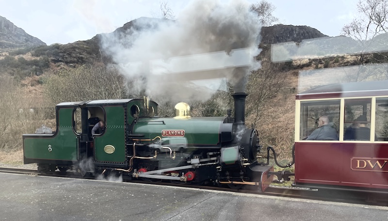 A green steam engine called Blanche, facing backwards and attached to a red carriage.