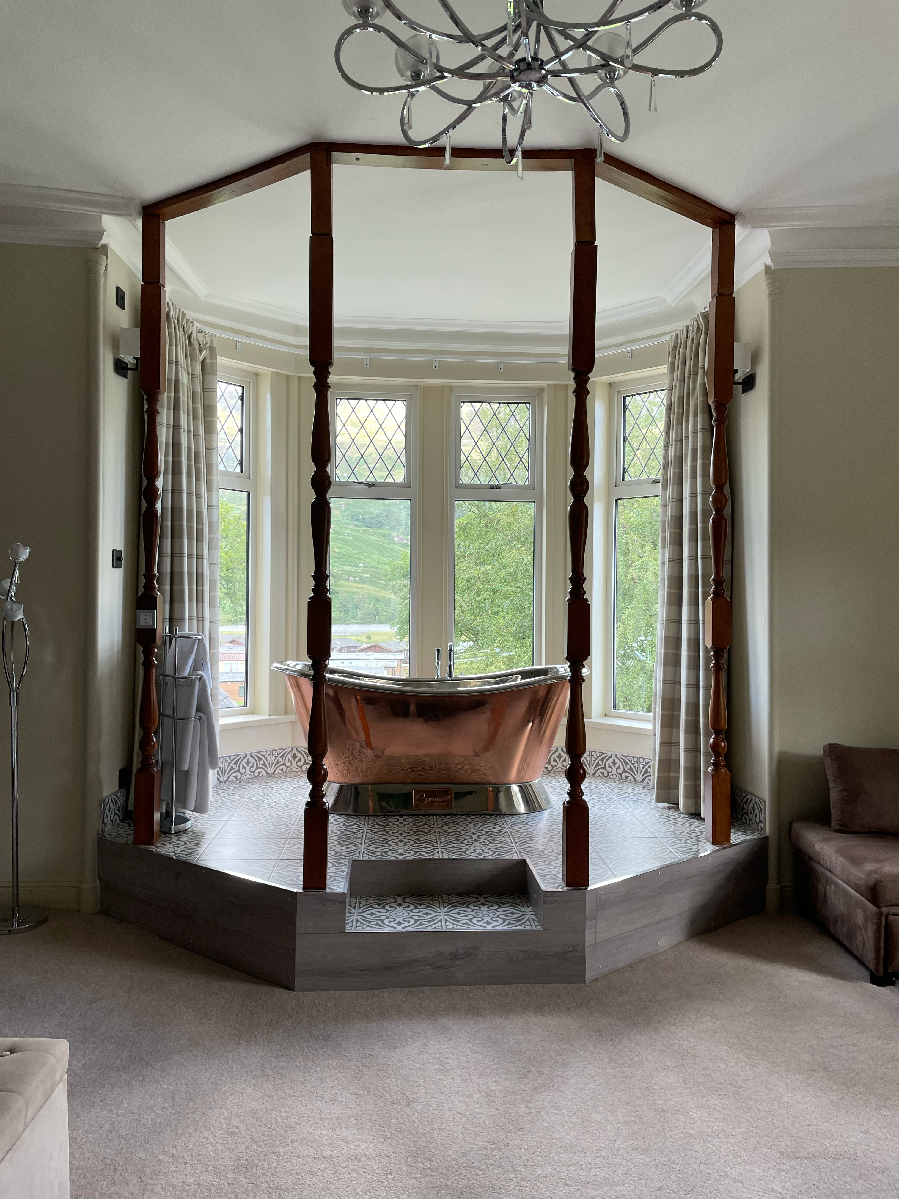 A large copper bath on a raised dias before a bay window.