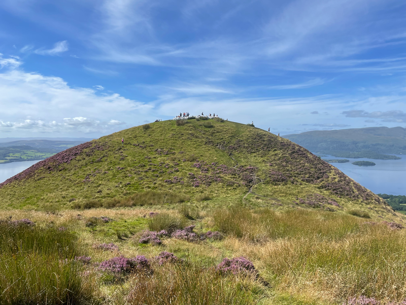 A very semi-circular hill with white bags of stone and people on the top.